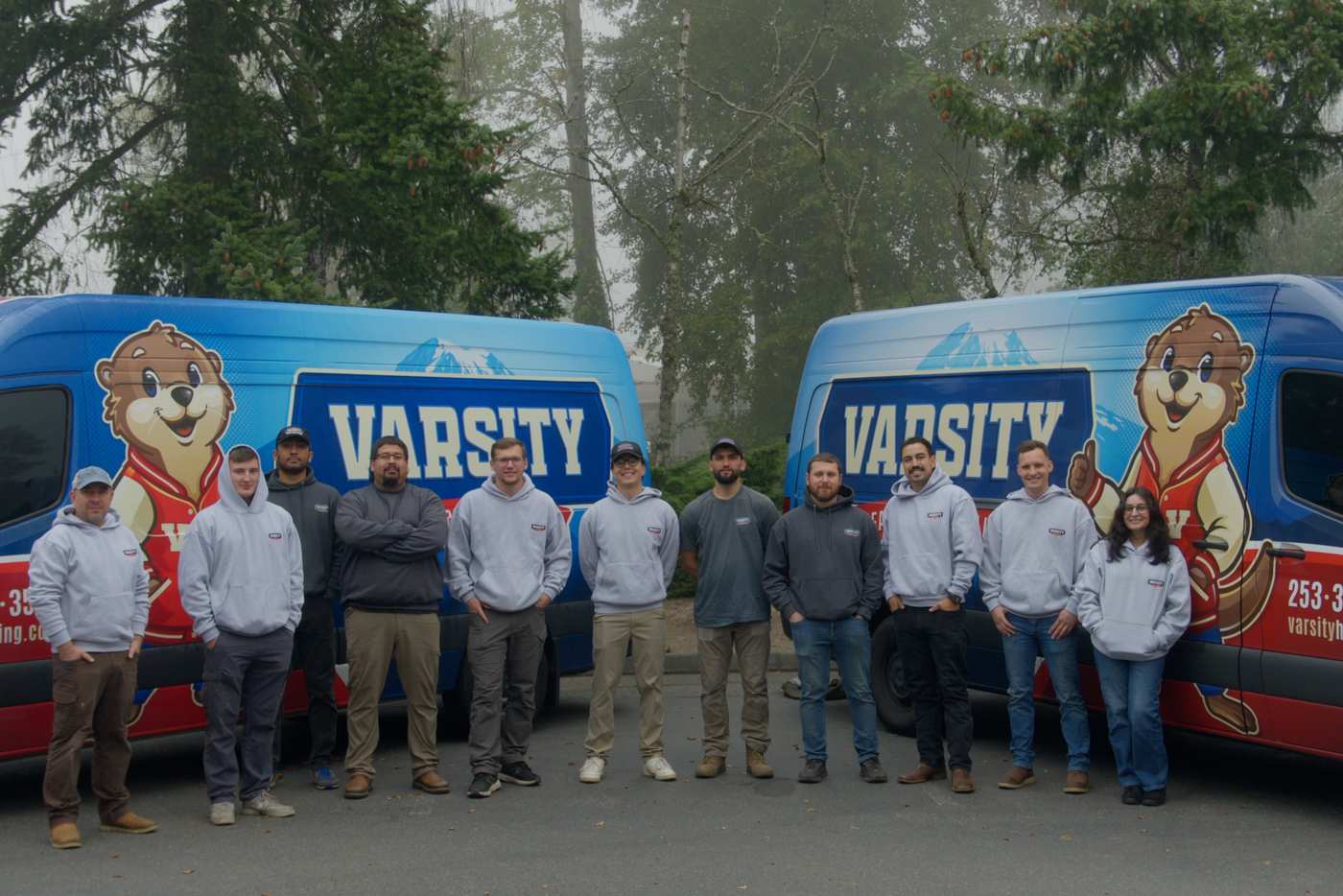 The Varsity Heating and Cooling team standing in front of three Varsity vans